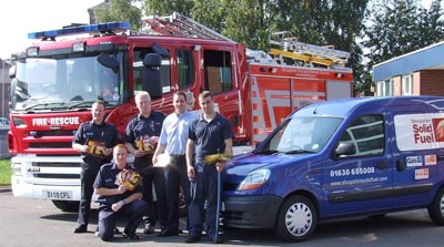 Firefighters and chimney sweep pose in front of fire appliance and van