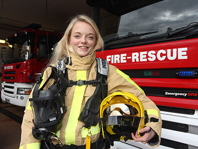 Laura Davies poses next to appliance in full protective kit holding a helmet under her arm