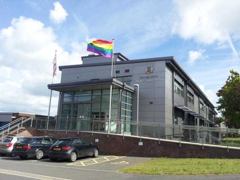Rainbow flag flying against blue sky over Fire Service Headquarters